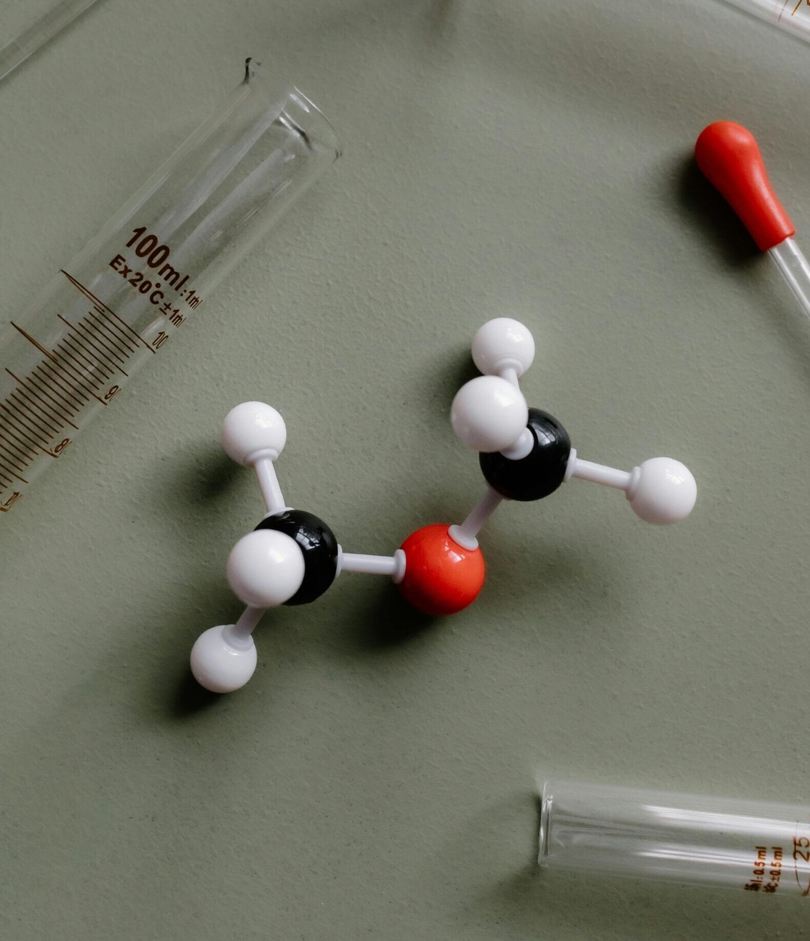 Close-up of a molecular model surrounded by laboratory equipment like pipettes and test tubes.